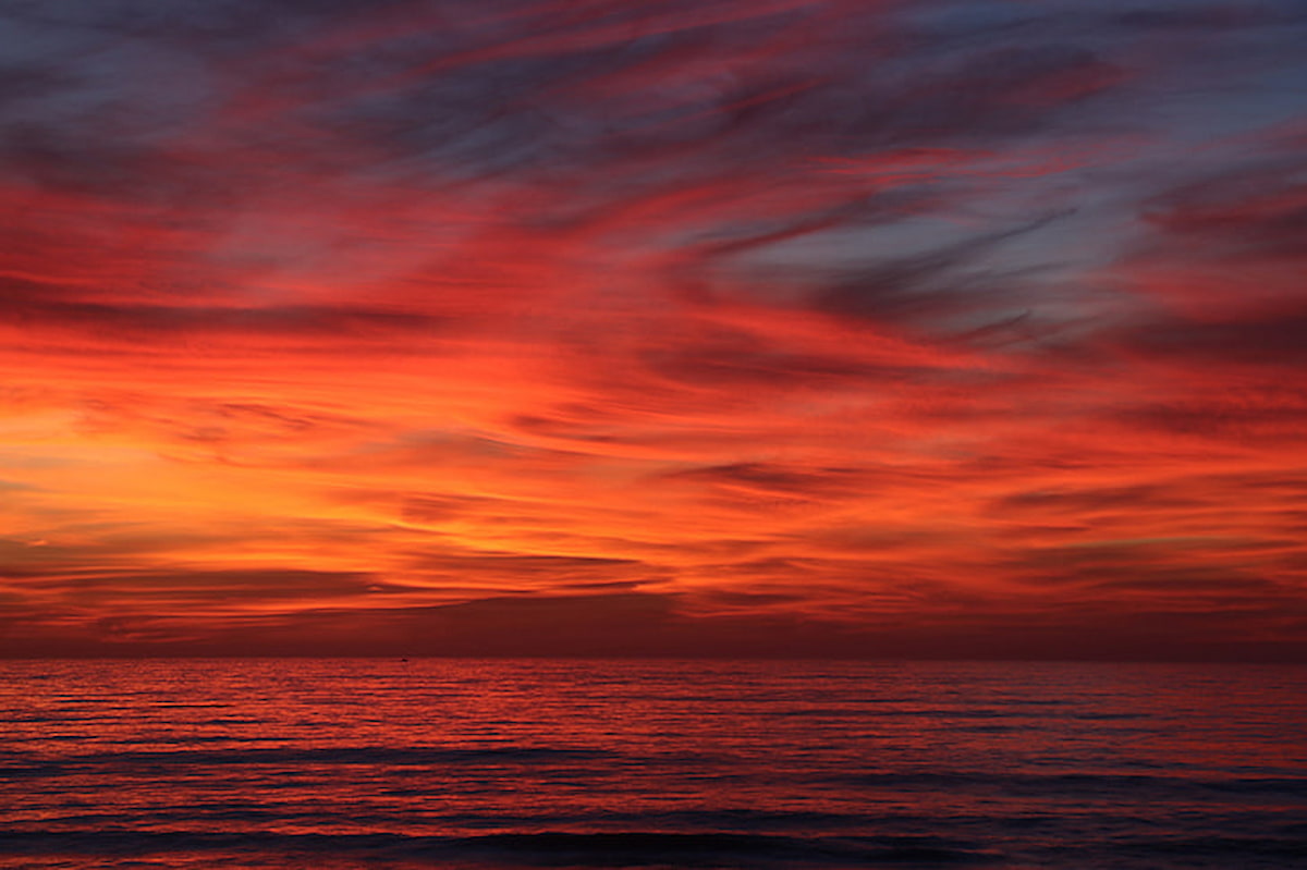 Vibrant red sunset sky over a calm sea.